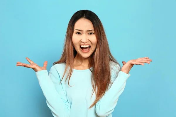 Portrait of angry Asian woman on color background — Stock Photo, Image