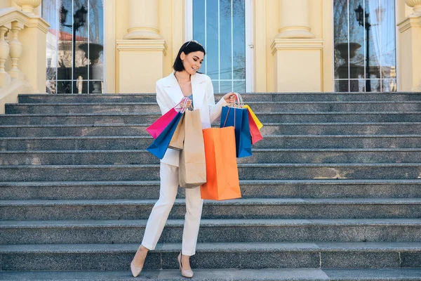 Szép fiatal nő bevásárlótáskákkal a lépcsőn a szabadban — Stock Fotó