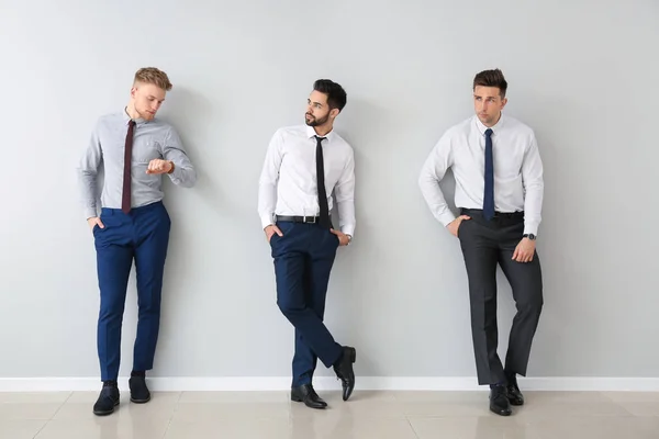 Fashionable young men near grey wall — Stock Photo, Image