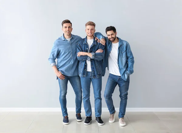 Fashionable young men near light wall — Stock Photo, Image