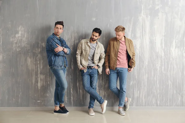 Fashionable young men near grey wall — Stock Photo, Image