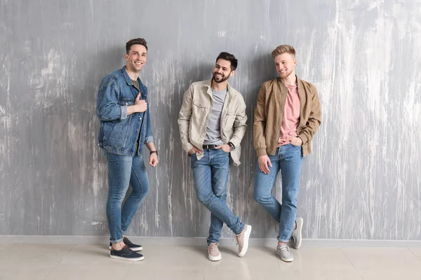Fashionable young men near grey wall — Stock Photo, Image