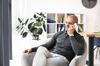 Afrikalı-Amerikalı adam evde telefonla konuşuyor