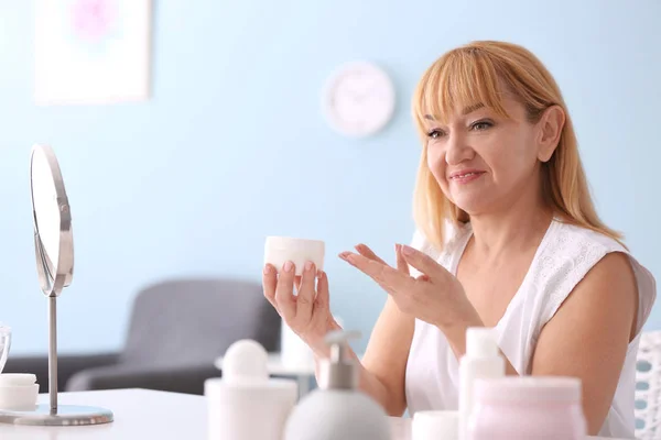 Mature woman with jar of cream at home — Stock Photo, Image