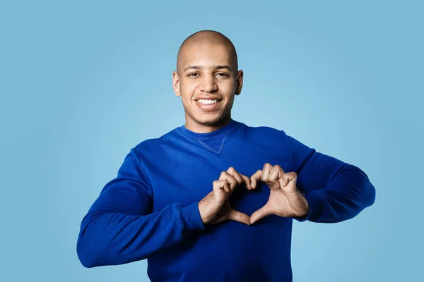 Handsome African-American man making heart with his hands on color background — Stock Photo, Image