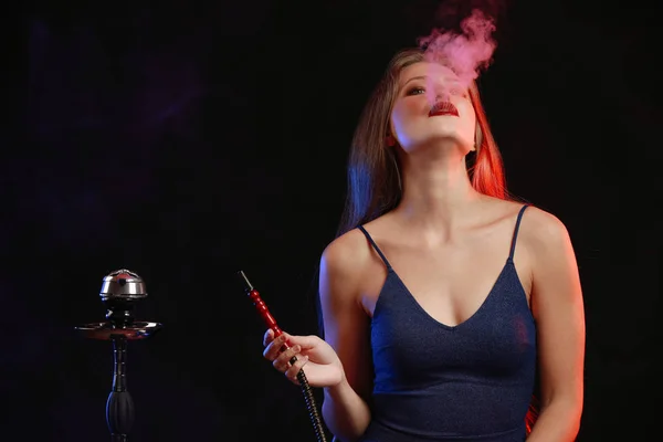 Ung kvinna rökning hookah på mörk bakgrund — Stockfoto