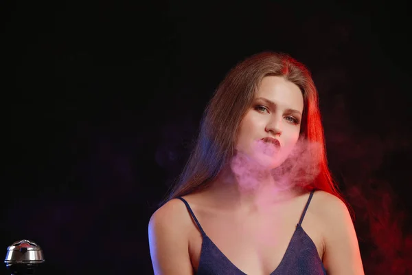 Young woman smoking hookah on dark background — Stock Photo, Image