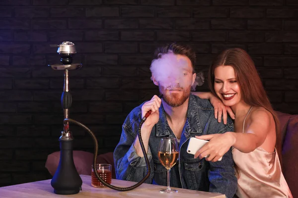 Young couple taking selfie while smoking hookah in cafe — Stock Photo, Image