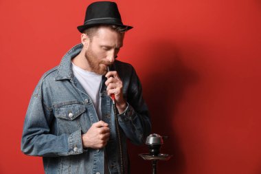 Genç adam arka planda nargile içiyor.