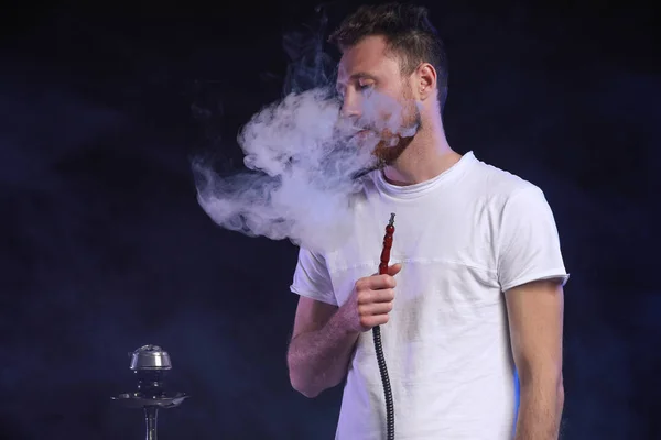Ung man röker hookah på mörk bakgrund — Stockfoto