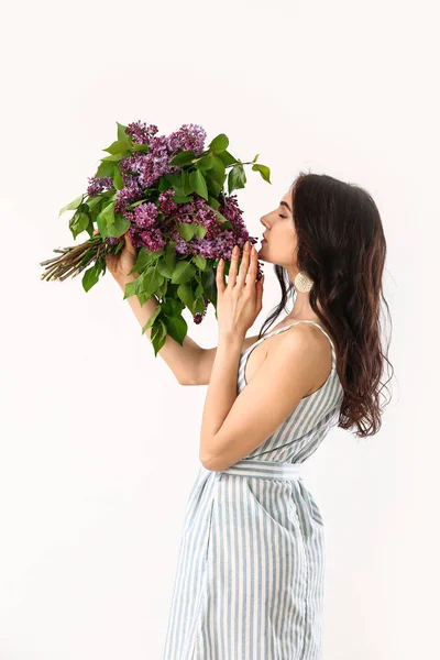 Beautiful young woman with bouquet of lilac flowers on white background