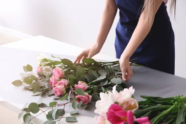 Çiçekçi ışık arka plana karşı masada buket yapma