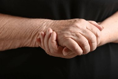 Koyu arka plan üzerinde kıdemli kadının Elleri