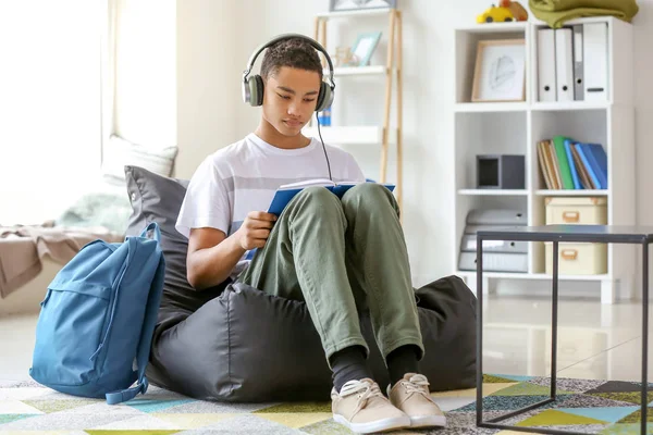 African-American teenage boy reading book at home — Stock Photo, Image