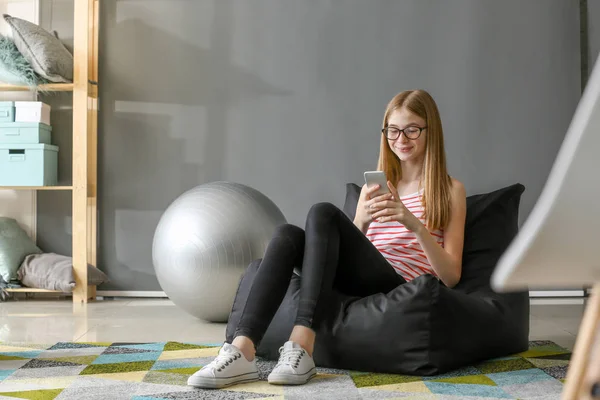 Söt tonårs flicka med mobiltelefon hemma — Stockfoto