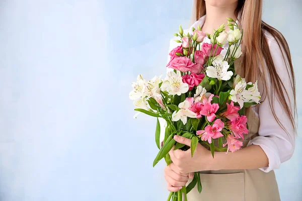 Young female florist with bouquet on color background — Stock Photo, Image