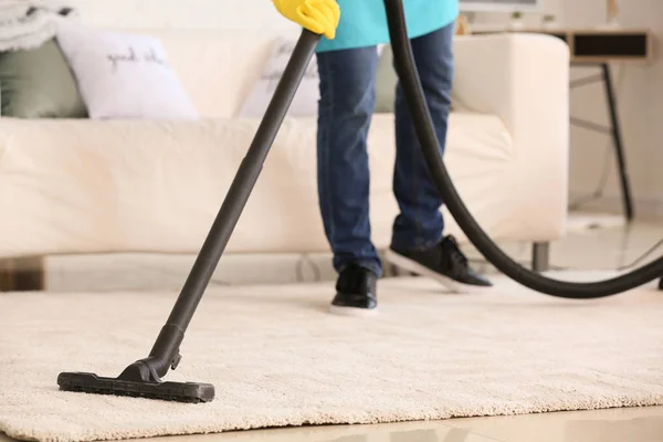 Hausmeister staubt Teppich in Wohnung — Stockfoto