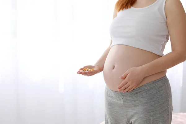 Jovem grávida com pílulas em casa — Fotografia de Stock