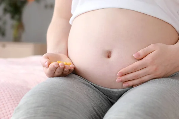 Jovem grávida com pílulas sentadas em casa — Fotografia de Stock