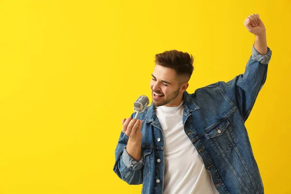 Handsome male singer with microphone on color background — Stock Photo, Image