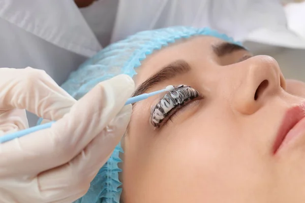 Young woman undergoing procedure of eyelashes dyeing and lamination in beauty salon — Stock Photo, Image