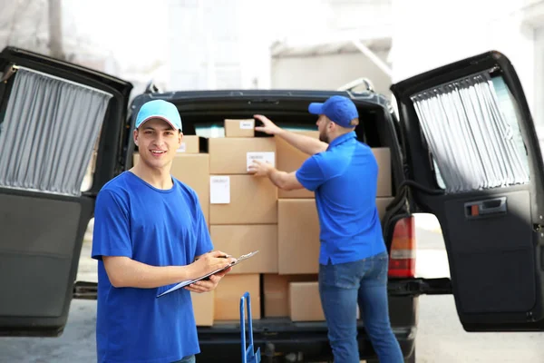 Delivery men taking parcels from car outdoors — Stock Photo, Image