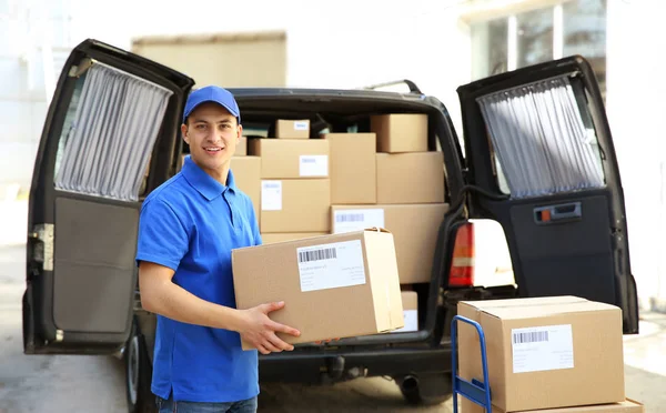 Schöner Zusteller in der Nähe von Auto mit Paketen im Freien — Stockfoto