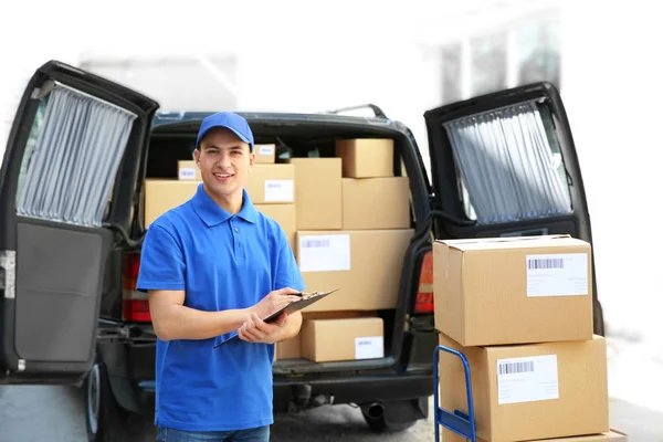 Handsome delivery man near car with parcels outdoors — Stock Photo, Image