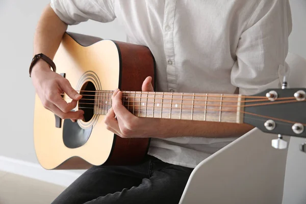 Красивий молодий чоловік грає на гітарі в приміщенні — стокове фото