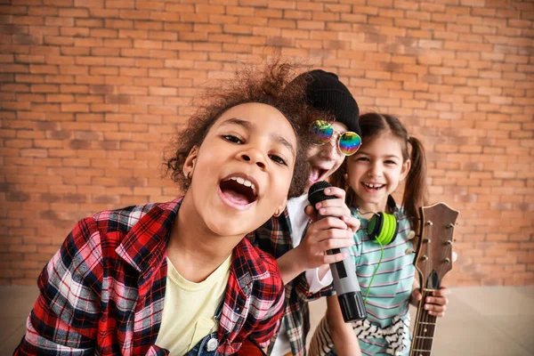 Группа маленьких музыкантов против кирпичной стены — стоковое фото