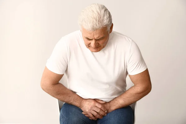 Hombre maduro con enfermedad urológica sobre fondo blanco —  Fotos de Stock