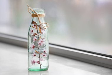 Pencere eşik üzerinde güzel çiçek dalı ile Şişe