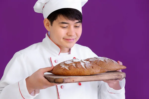 Boulanger asiatique avec du pain frais sur fond de couleur — Photo