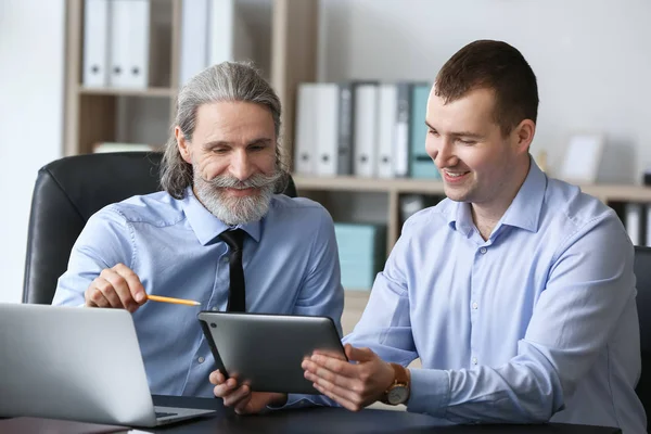 Mature businessman working with young colleague in office — Stock Photo, Image