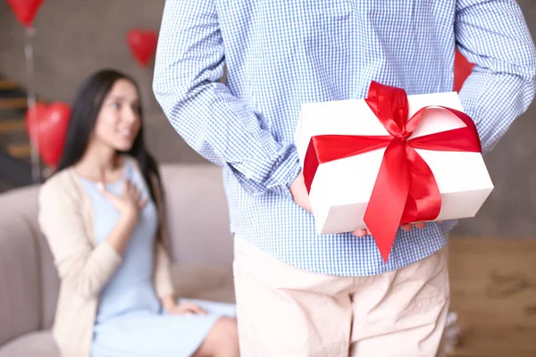 Young man hiding present for his wife behind back — Stock Photo, Image