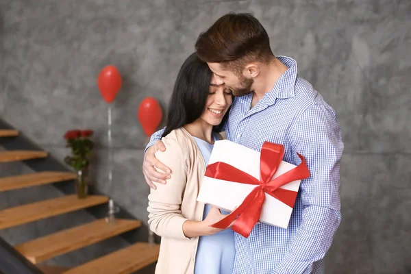 Pareja joven con presente en casa — Foto de Stock