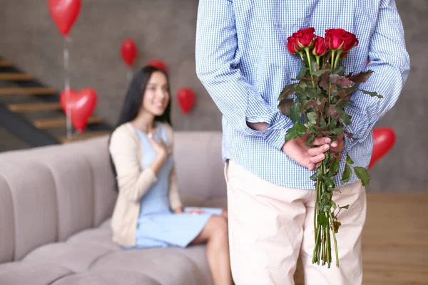 Young man hiding flowers for his wife behind back — Stok fotoğraf