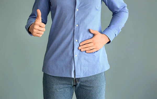 Hombre mostrando pulgar hacia arriba sobre fondo gris. Concepto de urología — Foto de Stock