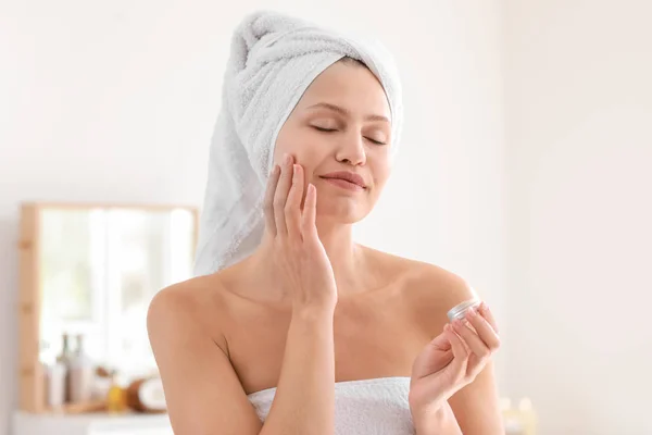 Hermosa joven aplicación de crema en casa — Foto de Stock