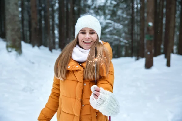 Beautiful woman with sparklers in winter forest — Stock Photo, Image