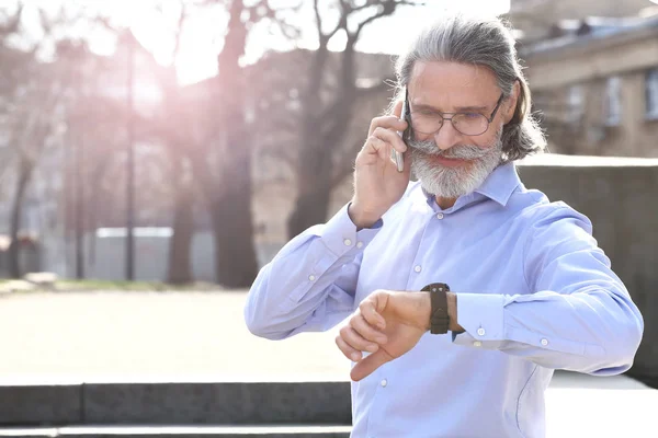 Handsome mature businessman talking by mobile phone outdoors — Stock Photo, Image