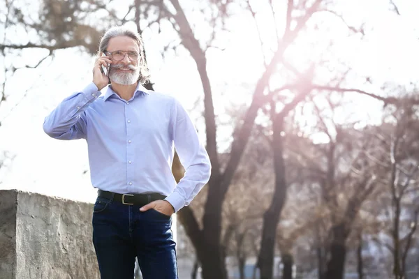 Handsome mature businessman talking by mobile phone outdoors — Stock Photo, Image