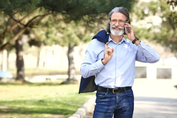 Handsome mature businessman talking by mobile phone outdoors — Stock Photo, Image