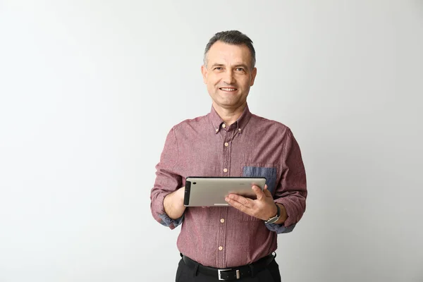 Przystojny dojrzały biznesmen z komputera typu Tablet na jasnym tle — Zdjęcie stockowe