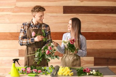 Çiçekçiler ahşap arka plan karşı masada buket yapma