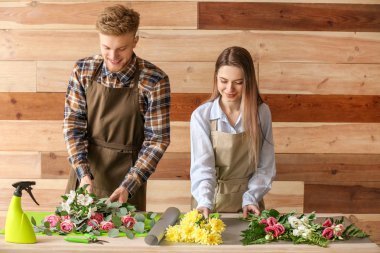Çiçekçiler ahşap arka plan karşı masada buket yapma