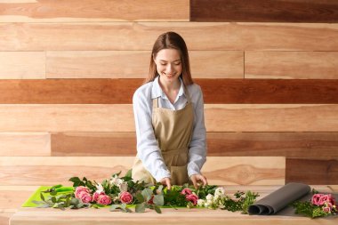 Çiçekçi ahşap arka plan karşı masada buket yapma