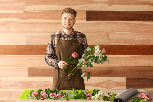 Male florist at table against wooden background — Stock Photo, Image