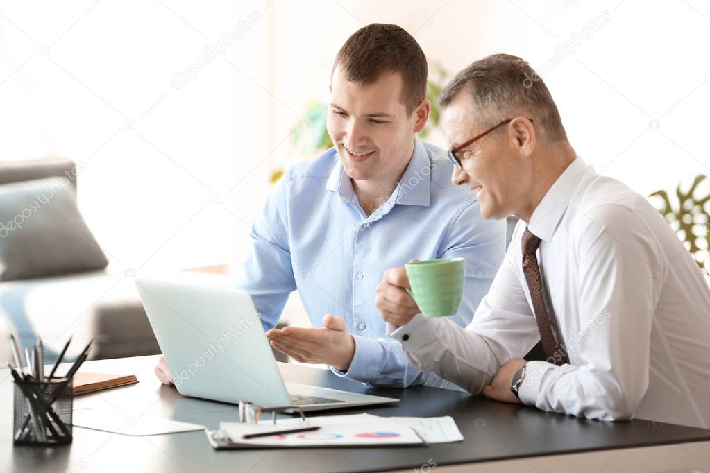 Handsome mature businessman with colleague working in office