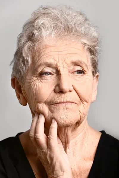 Ritratto di donna anziana su sfondo grigio — Foto Stock
